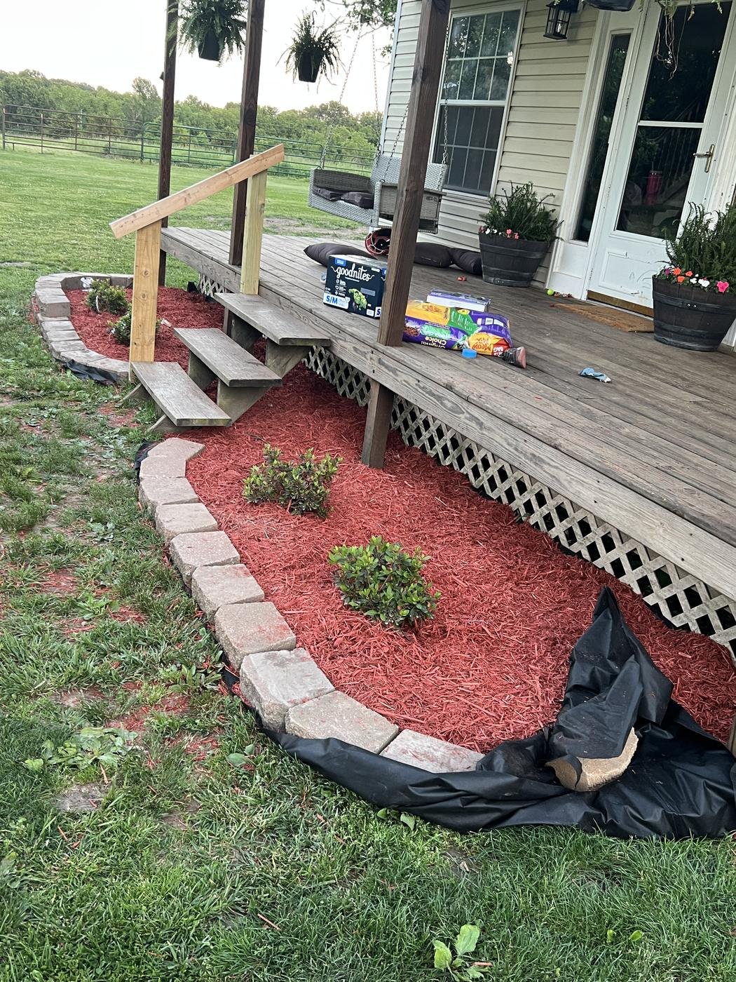 New porch steps and handrail with a mulched bed along the porch